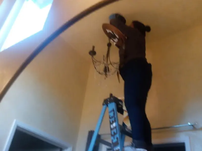 Electrician installing a chandelier in a Temescal Valley residence